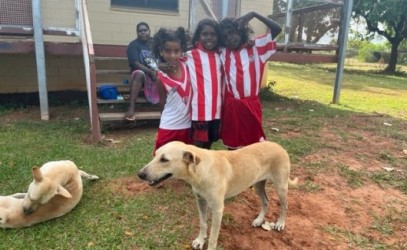 Three children playing with two dogs 