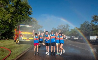 Participants of the Kakadu Triathlon celebrate their accomplishment under a refreshing water spray