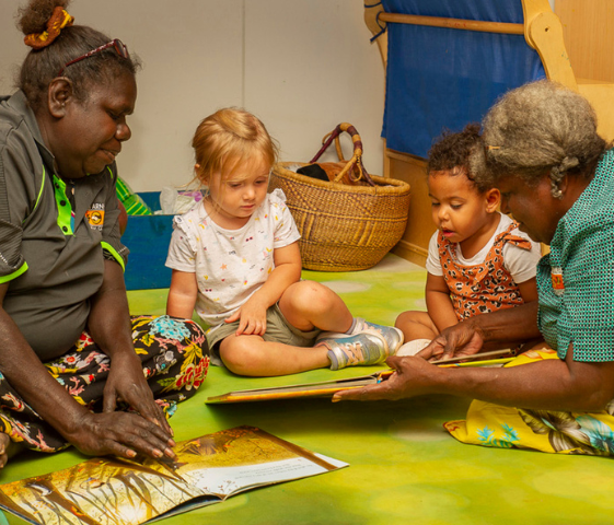 Two indigenous ladies reading stories to children