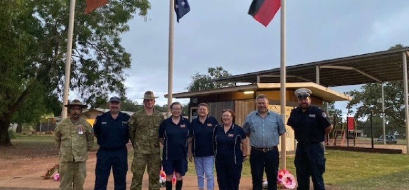 People standing under flags celebrating Anzac Day in Maningrida 