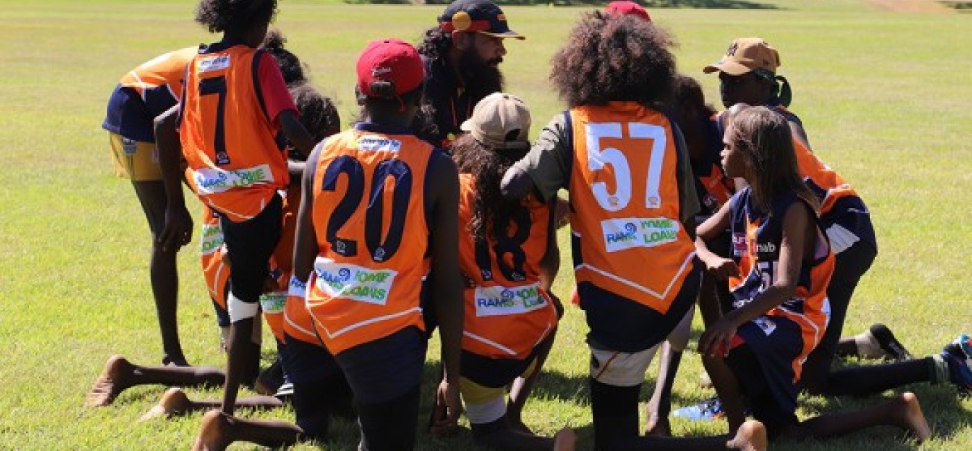 Children gathered around a football coach