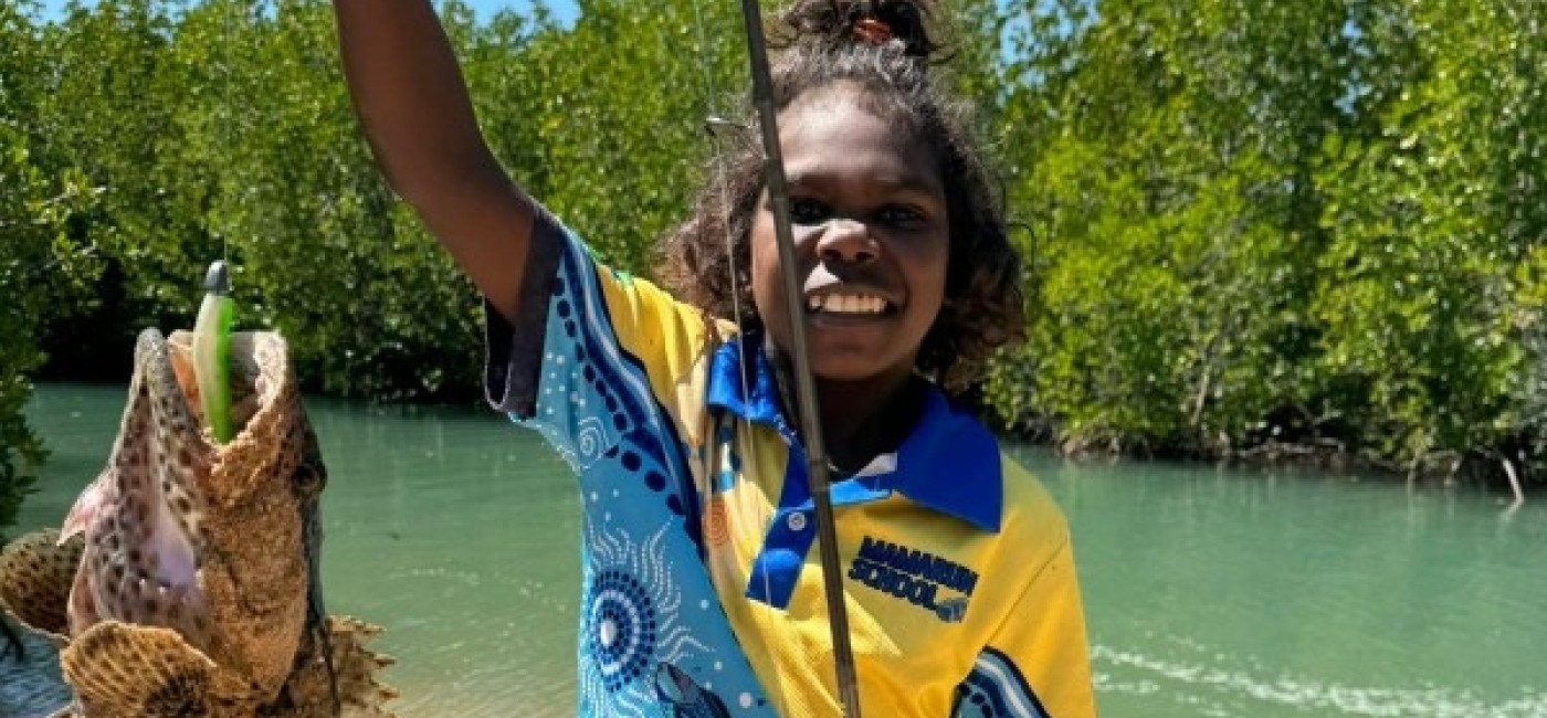 Young girl with a fish she caught by the edge of the river 